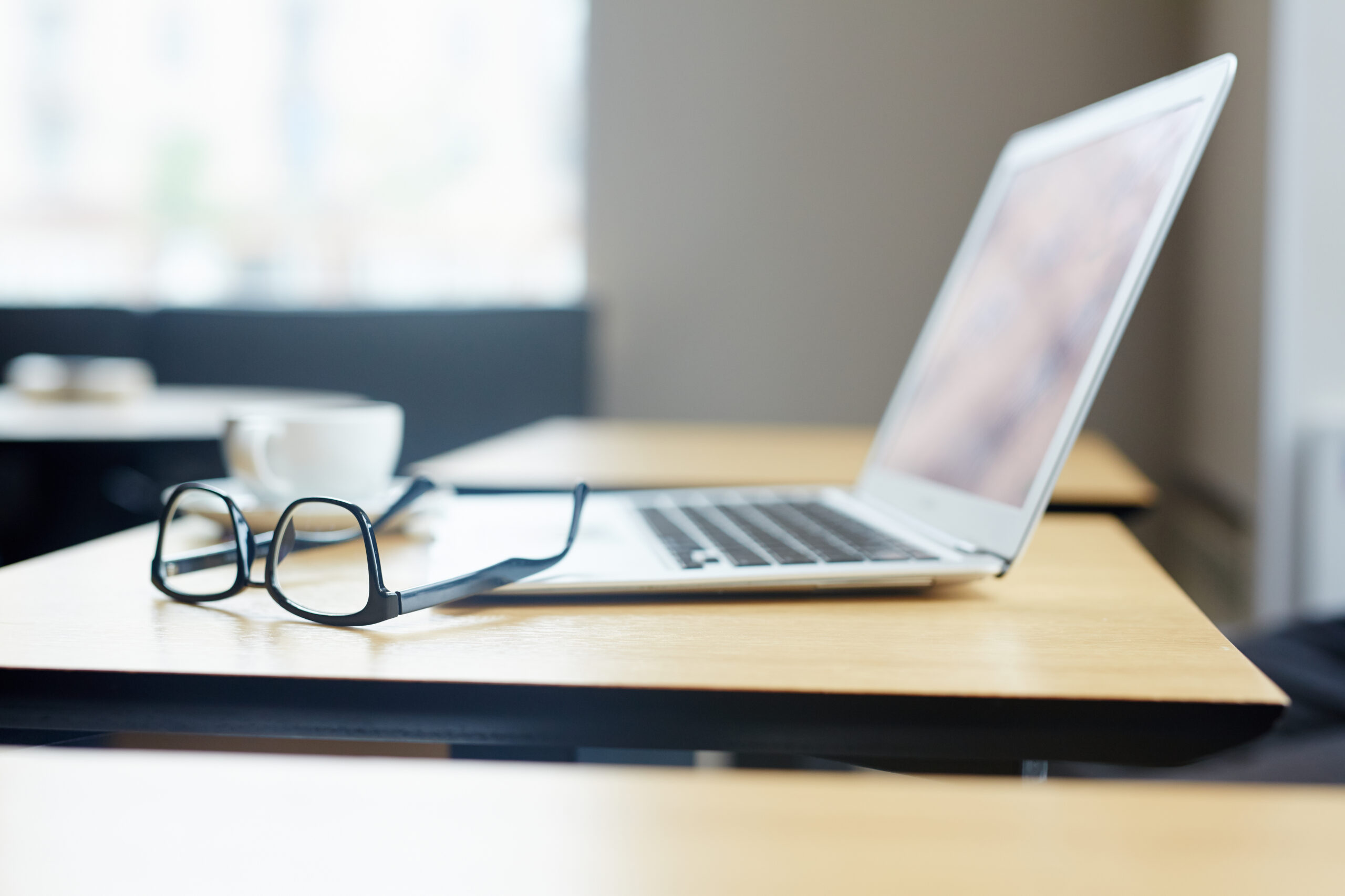 Brille und Laptop auf einem Schreibtisch im Büro