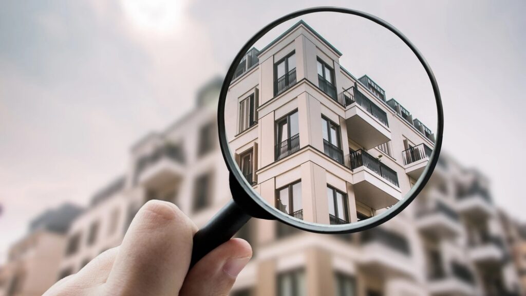 Außenansicht auf ein Haus mit mehreren Wohnungseinheiten durch eine Lupe