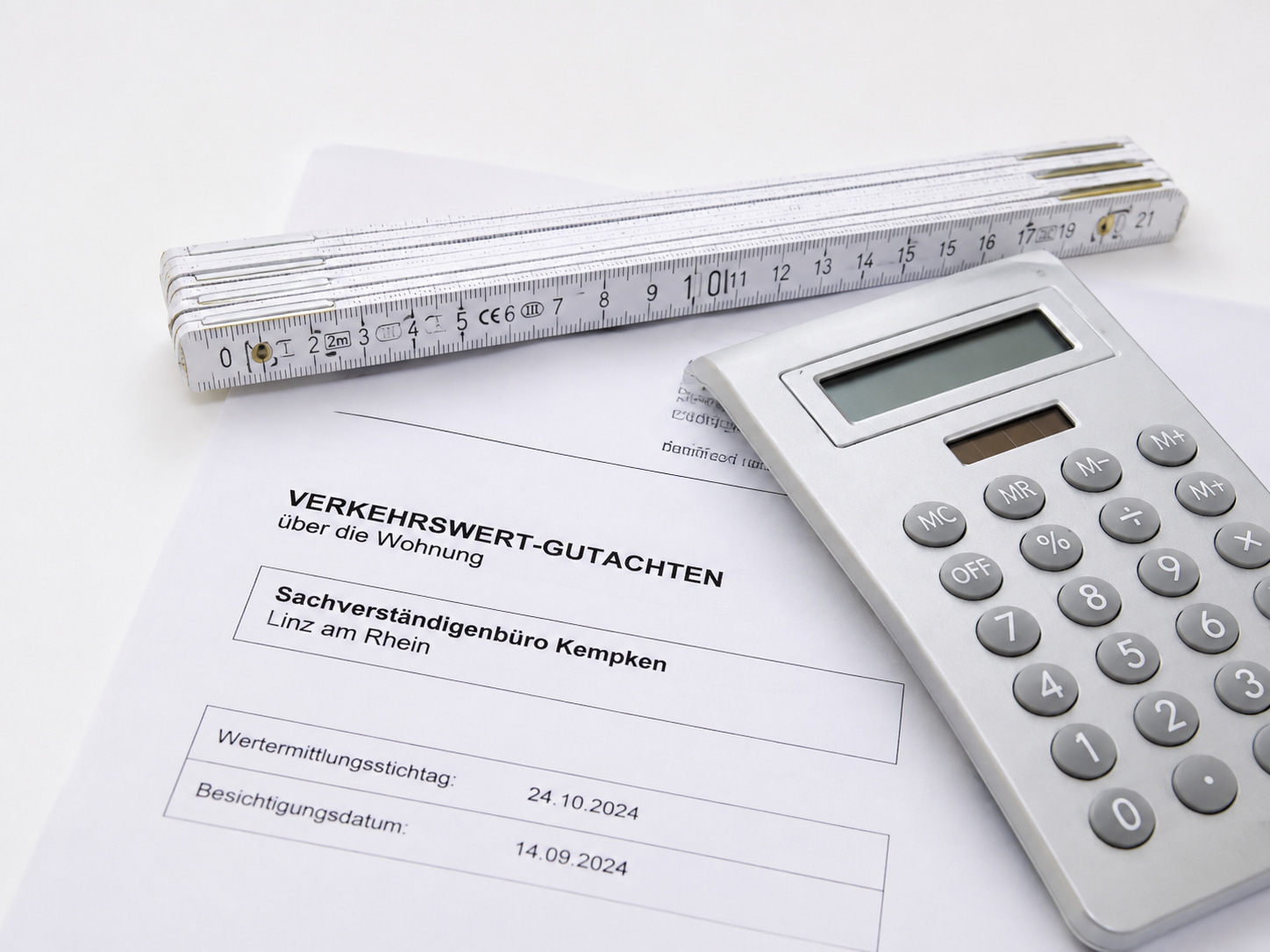 Zollstock, Taschenrechner und ein Gutachtendokument